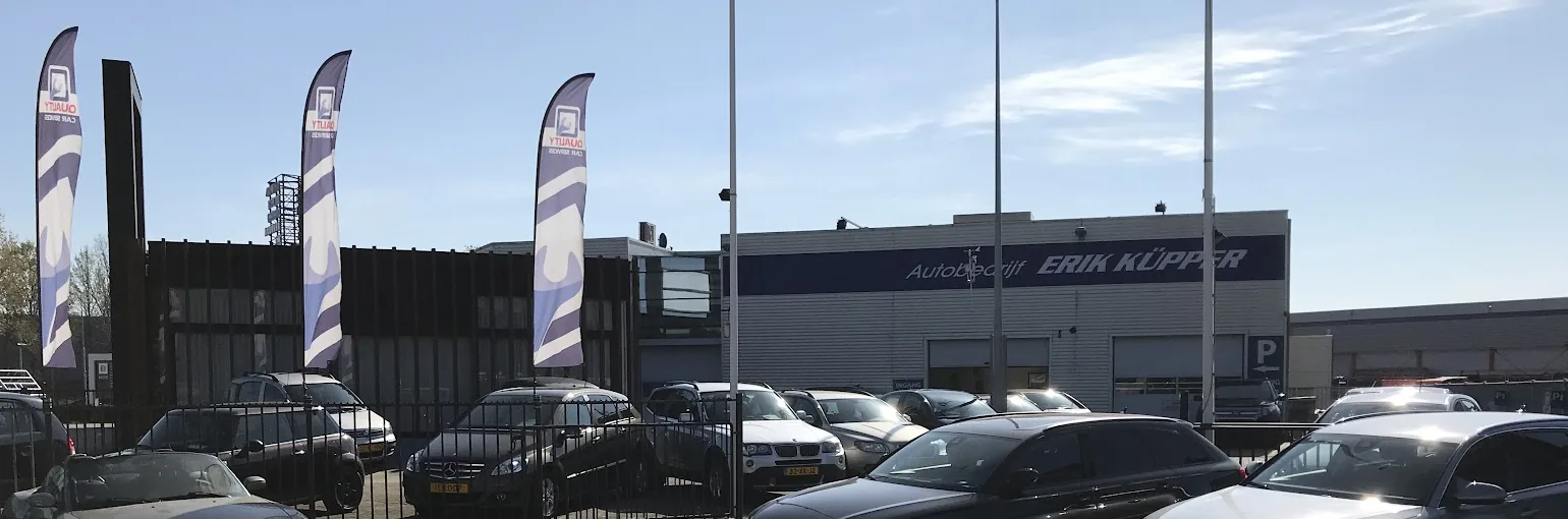 Het pand van Autobedrijf Erik Küpper met de blauwe gevelband en het verkoopterrein